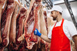 Man butcher standing in meat freezer holding hook