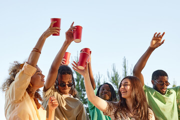 Wall Mural - Diverse group of people with hands in air dancing outdoors at Summer party