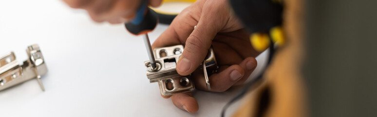 Wall Mural - Cropped view of man screwing nail from hinge of cupboard at home, banner