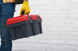 Leinwandbild Motiv Cropped view of man in glove holding tool box at home