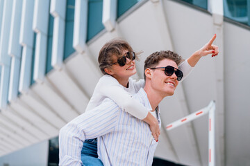 Happy young caucasian urban couple laughing and doing piggyback at outdoors