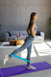 © F8  \ Suport Ukraine - Young woman during her fitness workout at home with rubber resistance band