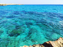 Sea Transparent Turquoise Water. The Rocky Coast Of The Island Of Mallorca Is Washed By Turquoise Clear Water. Shades Of The Summer Sea, Stones, Seabed. Summer Mood, Vacation. Landscape, Background