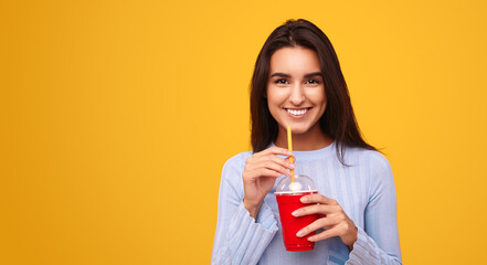 Content Hispanic woman drinking takeaway soda in yellow studio