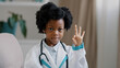 © Yuliia - Close-up african american little girl standing in medical clothes playing pretending to be doctor charming child looking at camera smiling shows OK sign gesture no problem future professions concept