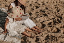 Stylish Girl With Mother Reading Book On Sandy Seashore