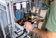 © Zoran Zeremski - Close up of male brewer hands in a brewery filling bottles with beer.