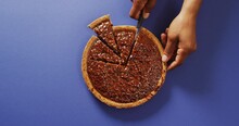 Video Of Hands Of Biracial Man Cutting Pie With Knife On Blue Background
