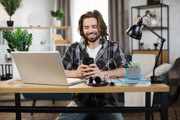 Wall Mural - Happy smiling businesswoman using modern smartphone for video chat at work. Young caucasian female sitting at modern bright office. Technology concept.