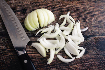 Wall Mural - Thinly Sliced Onion on a Dark Wood Cutting Board: Onion sliced into thin wedges with a chef's knife on a wood background