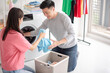 The husband and wife wash the laundry, using a washing machine, and the wife distinguishes the type and color of the clothes, allowing the husband to put the laundry in the washing machine.