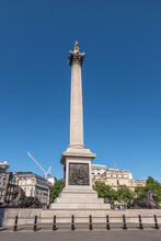 London, UK- July 4, 2022: Trafalgar Square. East Side Of Nelson's Column Against Blue Sky Showing High Commission Of Canada With Its Flag In The Back. Crane On Horizon. Some Green Foliage