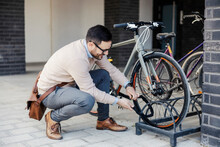 A Casual Businessman Locks Up His Bicycle On The Street.