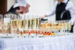 Stylish champagne glasses and food appetizers on table at wedding reception
