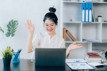 Portraits of beautiful smiling Asian women relax using laptop computer technology while sitting on their desks and using their creativity to work