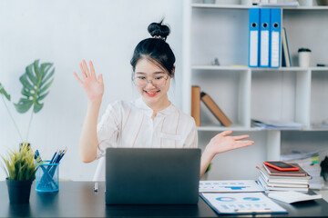 Portraits of beautiful smiling Asian women relax using laptop computer technology while sitting on their desks and using their creativity to work