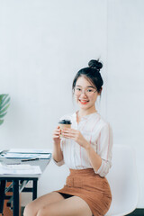 Portraits of beautiful smiling Asian women relax using laptop computer technology while sitting on their desks and using their creativity to work