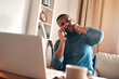 © Chanelle Malambo/peopleimages.com - Headache, stress and pain while talking on a phone call and working from a laptop at home. Worried, anxious man rushing to meet a deadline, looking unhappy while suffering from neck pain and tension