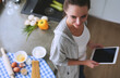 © lenets_tan - Smiling woman online shopping using tablet and credit card in kitchen