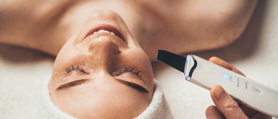 Wall Mural - close-up portrait of smiling woman receiving ultrasound cavitation facial peeling. skin treatment. f