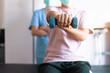 © gballgiggs - Physiotherapist women training with men patient using dumbbells in clinic,Physical therapy concept