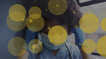 Poster - Animation of yellow spots of light over african american female health worker removing face mask