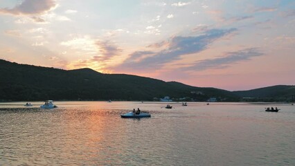 Wall Mural - Many boats and catamarans floating in calm lake. Water surface with reflections of sunset soft lights on it. Beautiful evening by the lake