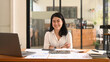 © Prathankarnpap - Confident asian woman employee sitting with arms crossed at her workplace and smiling to camera