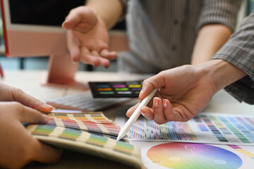 Close up view team of graphic designers working with color swatches and brainstorming for new project at co working space