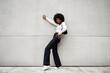 © fotofabrika - Black woman with afro hair posing in front of a gray concrete wall
