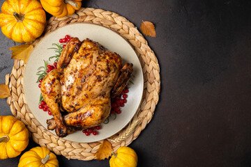 Wall Mural - Baked chicken for Thanksgiving Day. Roasted chicken or turkey with herb rosemary and berry and pumpkins for thanksgiving dinner on dark table. Festive table settings for Thanksgiving Day. Copy space