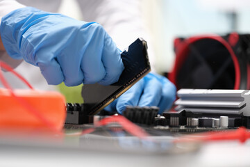 Wall Mural - Repair engineer holds RAM chip with hands and inserts RAM of computer into socket of computer motherboard