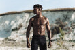 muscular African American man posing shirtless outdoors on the beach. African fitness model with muscular inflated body