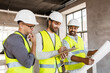 © Syda Productions - architecture, construction business and people concept - male architects in helmets with clipboard discussing blueprint in office building