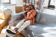 © Syda Productions - moving, people and real estate concept - tired woman with boxes sitting on sofa at new home