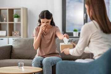 Wall Mural - psychology, mental health and people concept - crying woman patient taking paper tissue from psychologist at psychotherapy session