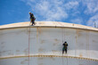 © chitsanupong - Male two worker inspection wearing safety first harness rope safety line working at a high place on tank roof spherical
