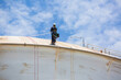 © chitsanupong - Male worker inspection wearing safety first harness rope safety line working at a high place on tank roof spherical gas  blue sky