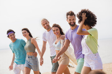 Wall Mural - Portrait of cheerful excited fellows hug hold hands walk sand beach chatting have good mood chilling outside