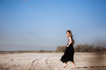 A young European woman is dancing on the beach waving a long black skirt. Feeling of freedom and independence. Unlimited possibilities. Movement to the goal. Summertime.