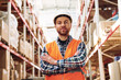 © standret - Standing with arms crossed. Employee in uniform is working in the storage at daytime