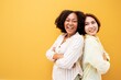 © Chalermphon - Portrait of two Diversity friend cheerful young women standing together and looking at camera isolated over yellow background.African Asian woman friendship difference culture concept.
