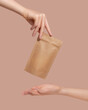 Woman's hands hold cardboard packages for tea or snacks on a beige background. Tea branding and packaging mockup.