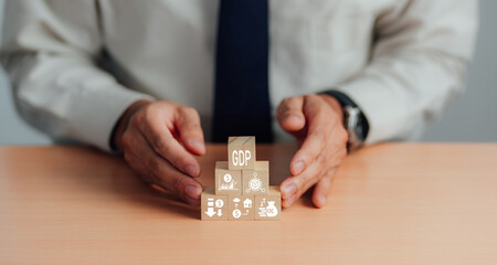  GDP, symbol of gross domestic product Businessman holding a wooden block with an icon saying 'GDP' copy space. Business and GDP growth. Gross domestic product concept.