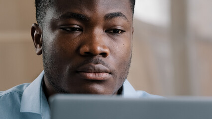 Serious male young african american businessman programmer typing on computer at home office focused concentrated millennial confident guy use laptop create web design for startup research information