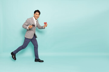 young asian businessman showing two credit card isolated on green background, full body composition