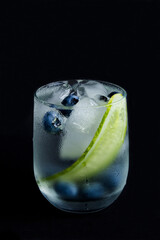 Wall Mural - Drink with cucumber, mint and blueberry in the drinking glass on the dark background. Closeup. Location vertical.