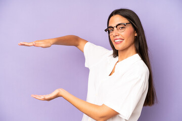 Wall Mural - hispanic pretty woman smiling, feeling happy, positive and satisfied, holding or showing object or concept on copy space