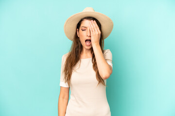 Wall Mural - young adult pretty woman looking sleepy, bored and yawning, with a headache and one hand covering half the face