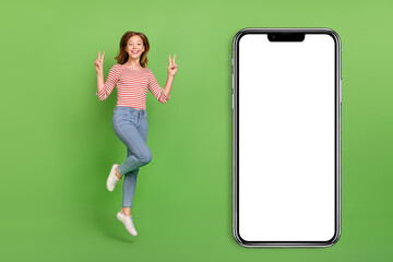 Sticker - Photo of cheerful friendly lady jump show v-signs wear striped shirt jeans sneakers isolated green color background